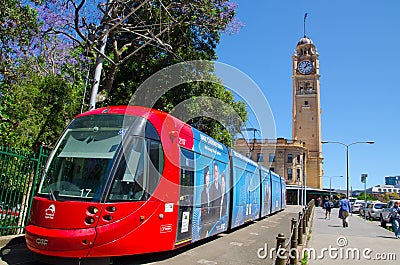 Red light rail running on the track at Pitt St. with Iconic central railway station clock tower at the background. Editorial Stock Photo